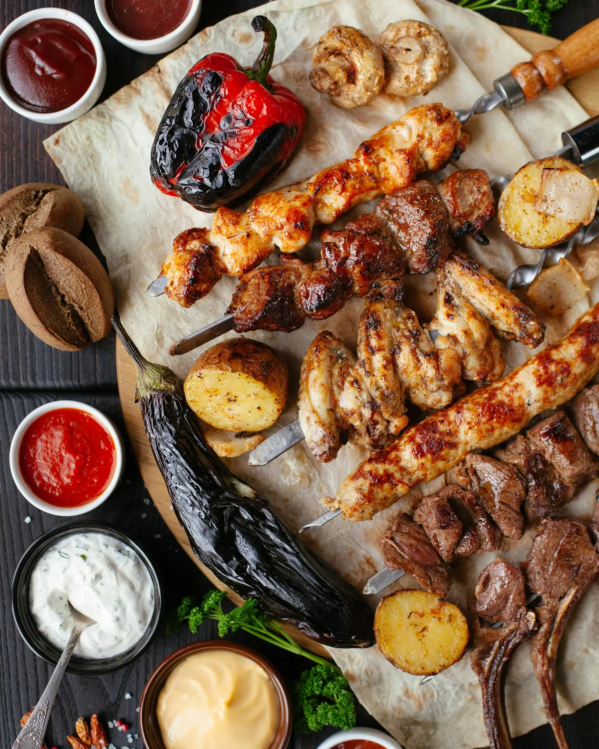 Brochettes, poulet grillé, légumes grillés et sauces sur une planche